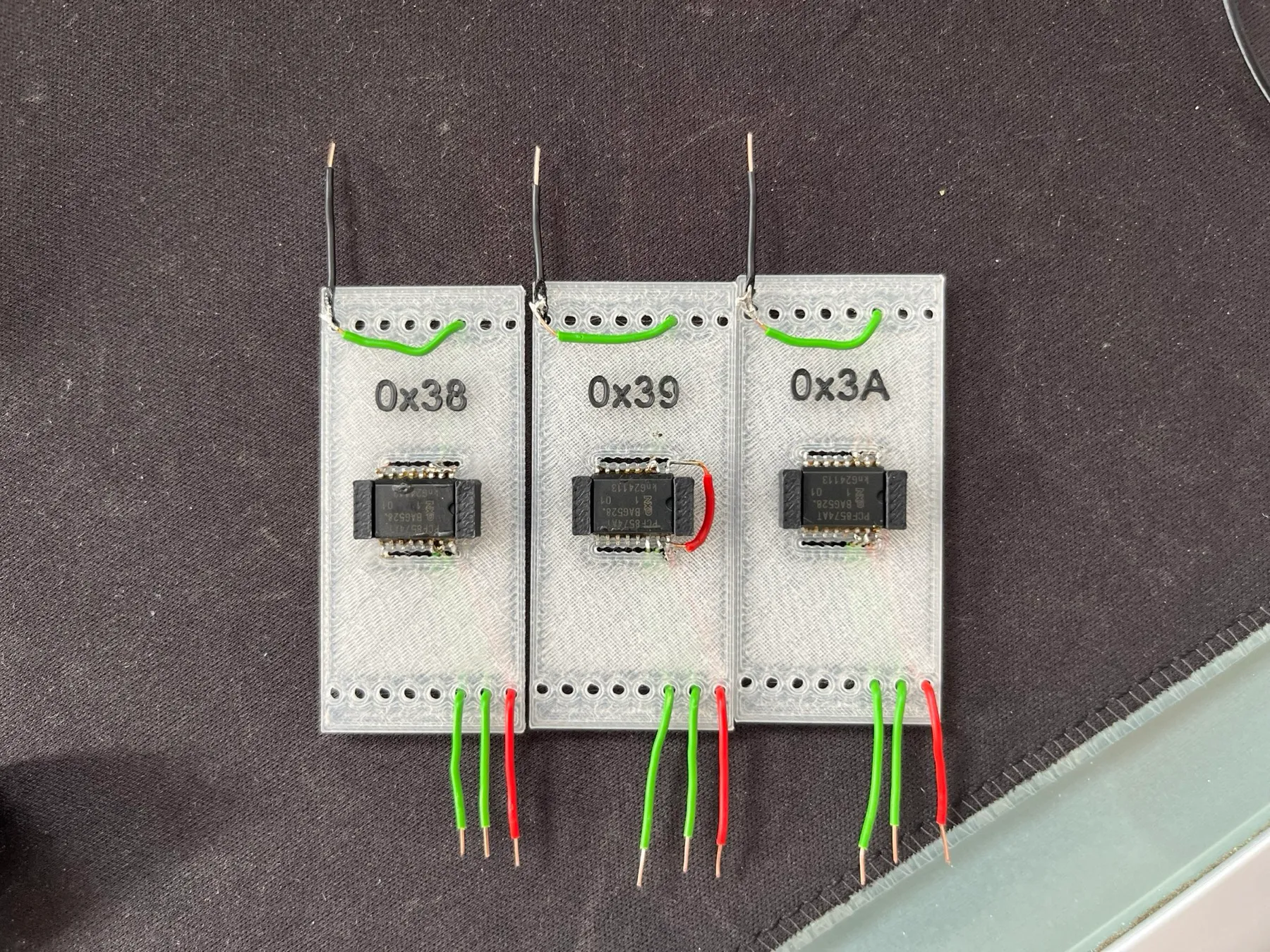 Three clear 3D-printed carrier boards, each holding a chip, labelled 0x38, 0x39 and 0x3A.